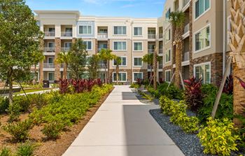An exterior view of an apartment building with a sidewalk and landscaping